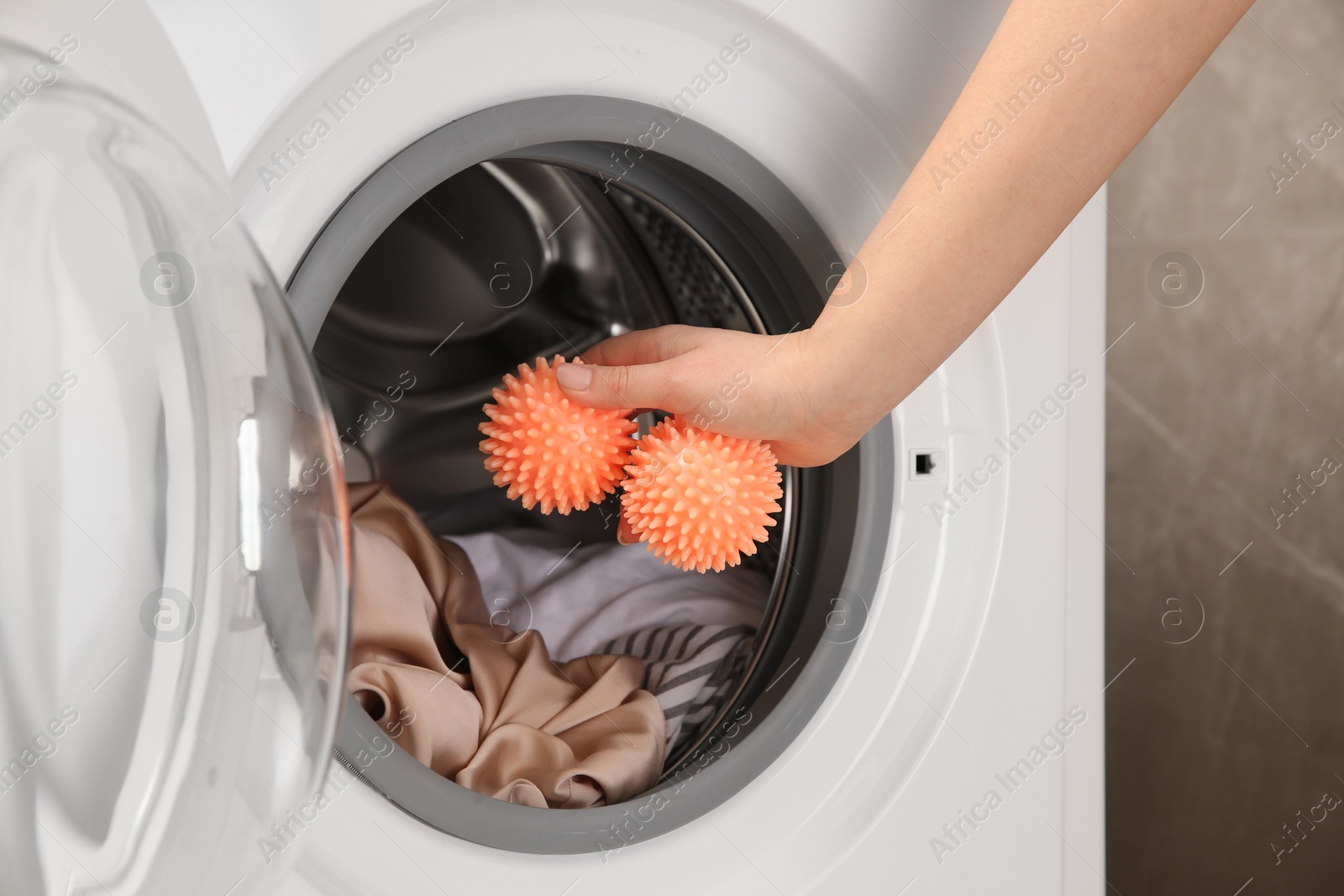 Photo of Woman putting dryer balls into washing machine, closeup