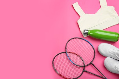 Photo of Rackets, sportswear and bottle on pink background, flat lay with space for text. Playing badminton