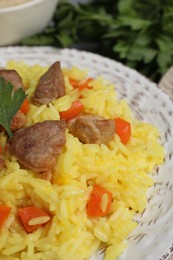 Photo of Delicious pilaf with meat and carrot on white plate, closeup