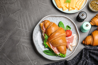 Photo of Flat lay composition with tasty croissant sandwich on grey table, space for text