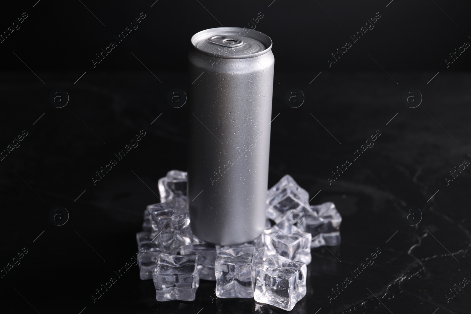 Photo of Aluminium can of energy drink and ice cubes on black table