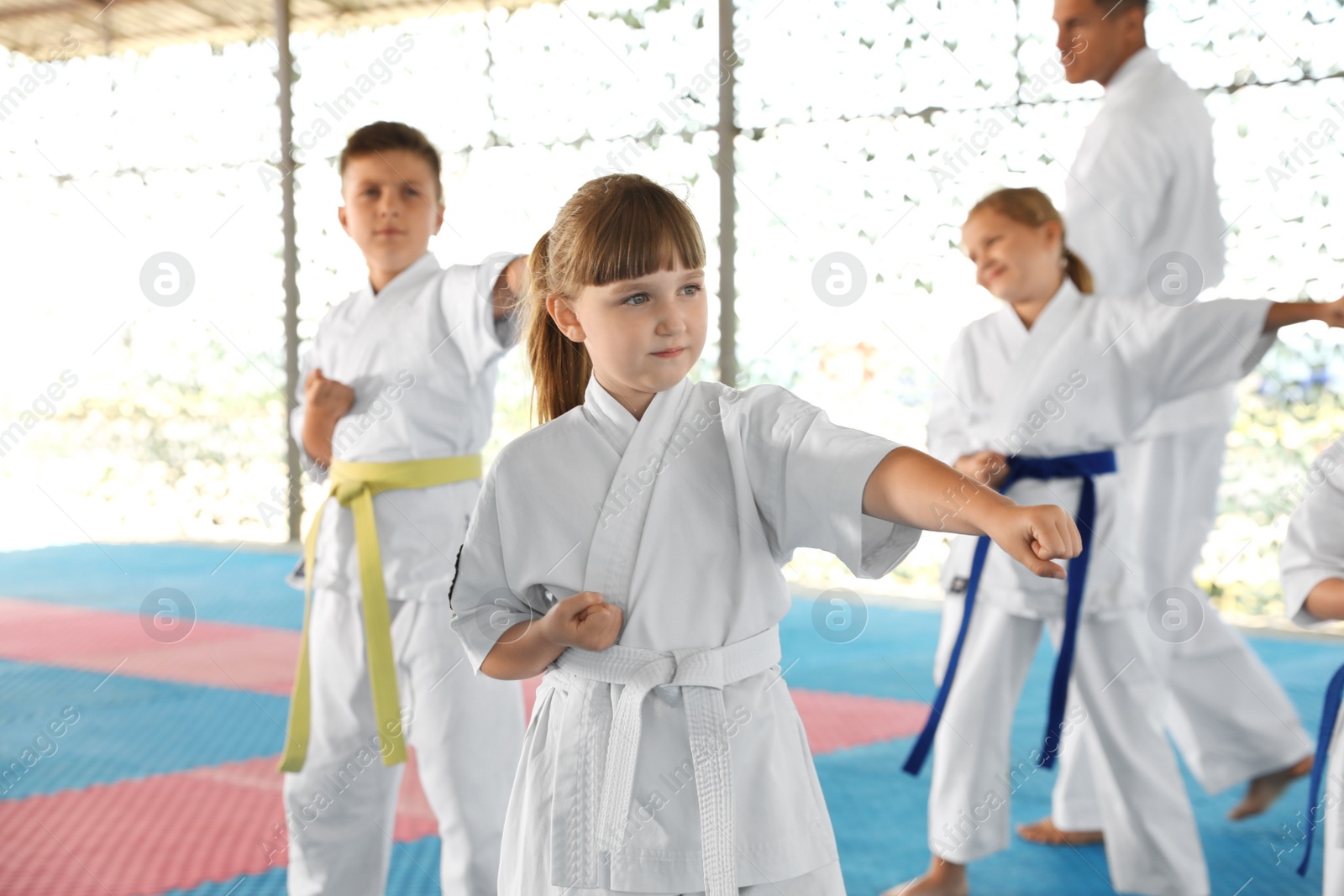 Photo of Children in kimono practicing karate on tatami outdoors