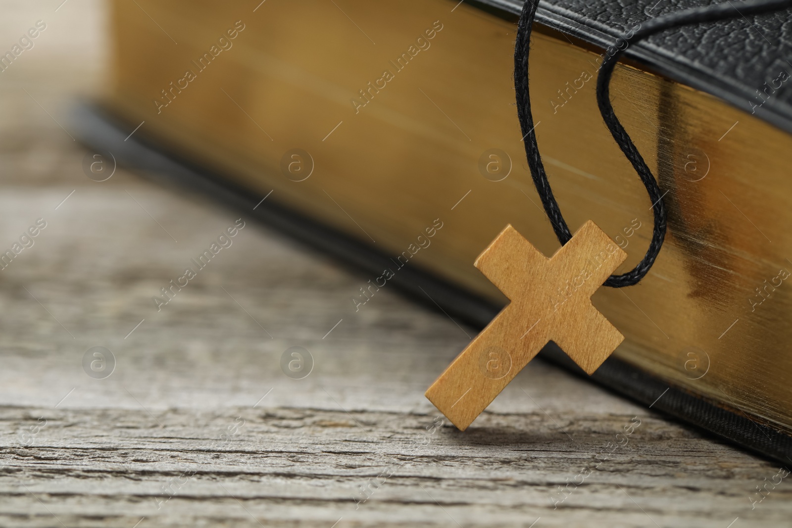 Photo of Christian cross and Bible on white wooden table, closeup