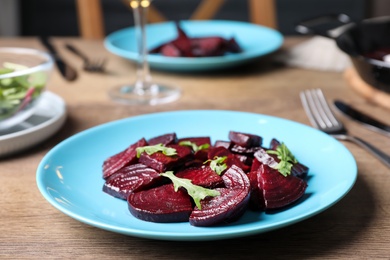 Photo of Roasted beetroot slices with arugula on wooden table, closeup