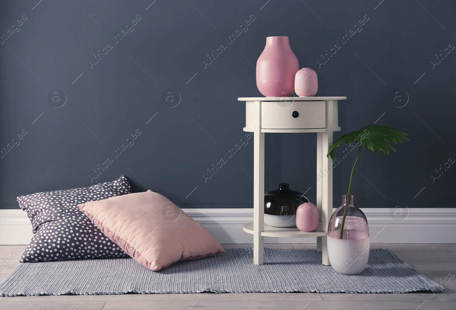 Photo of Living room interior with pillows, vases and table near dark wall. Space for text