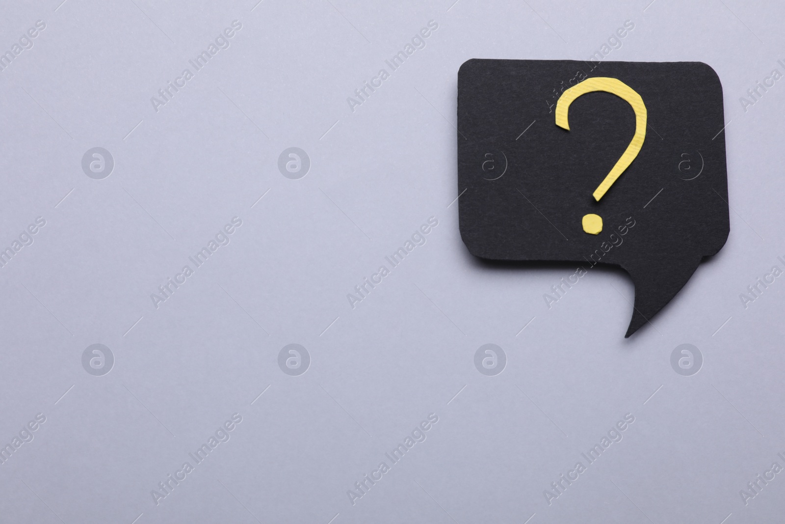 Photo of Paper speech bubble with question mark on light grey background, top view. Space for text