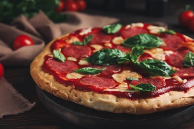 Pita pizza with pepperoni, cheese and basil on wooden table, closeup
