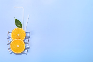 Photo of Slices of juicy orange, ice cubes and leaf on light blue background, flat lay. Space for text
