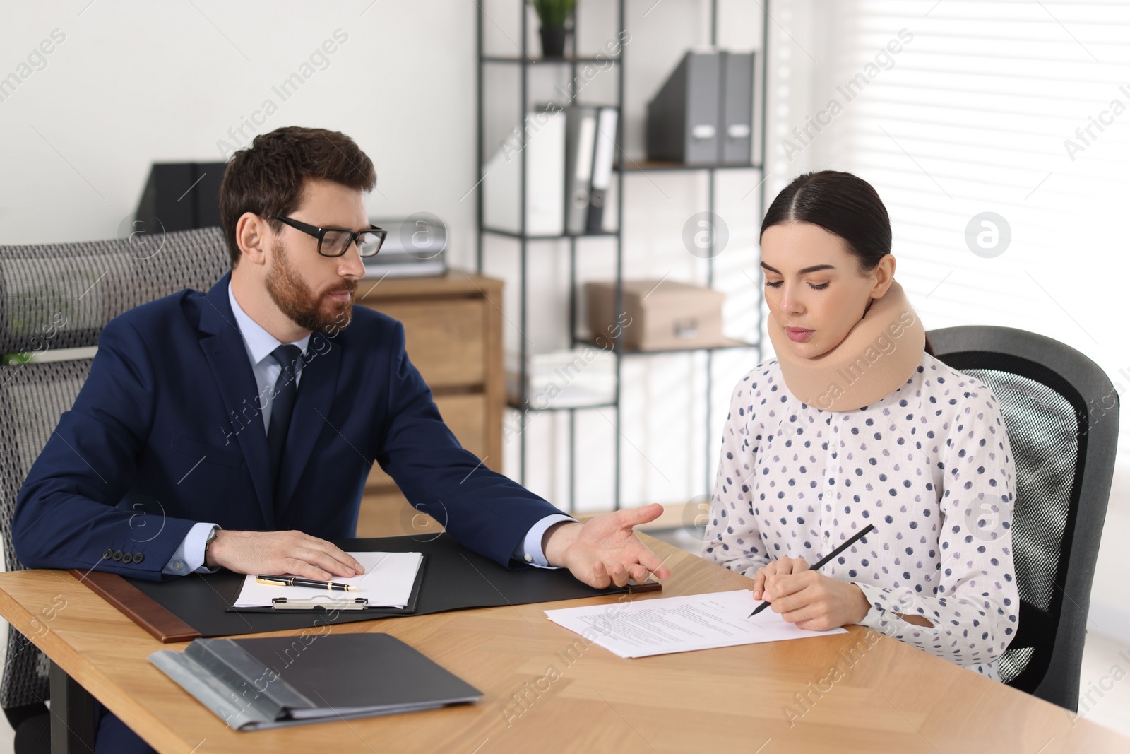 Photo of Injured woman signing document in lawyer's office