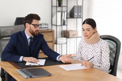 Injured woman signing document in lawyer's office