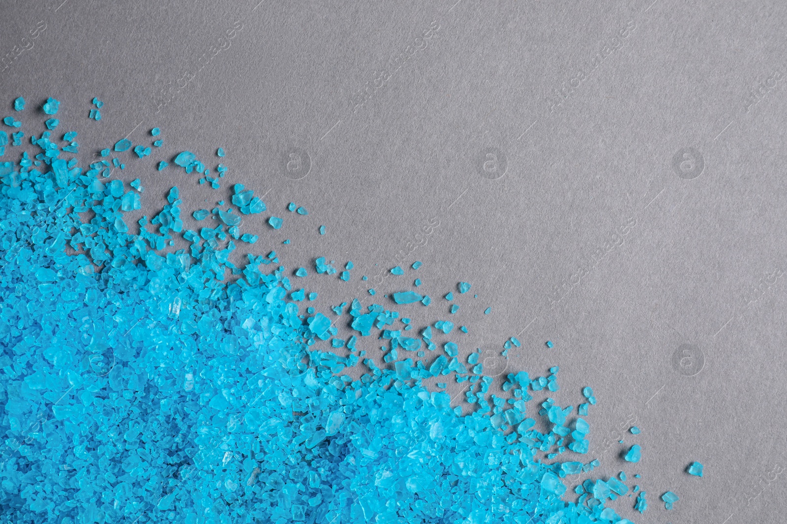 Photo of Light blue sea salt on grey table, top view. Space for text