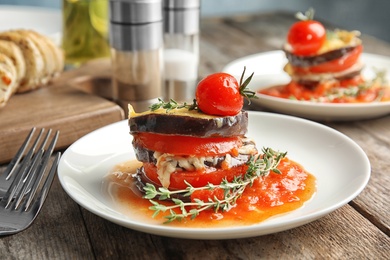 Photo of Baked eggplant with tomatoes, cheese and thyme on wooden table