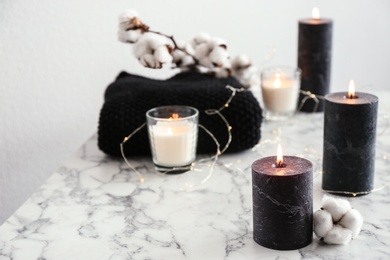 Photo of Burning candles and cotton flower with fairy lights on marble table