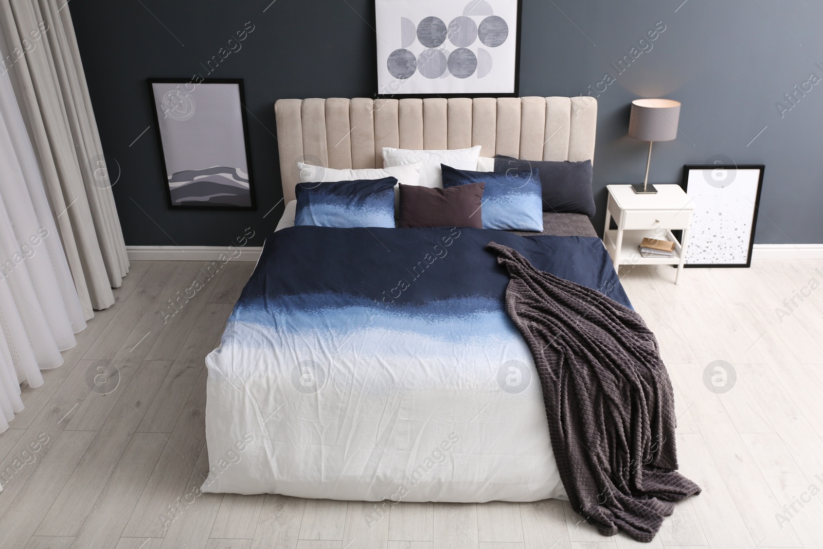 Photo of Comfortable bed with pillows and soft blanket in room. Stylish interior design