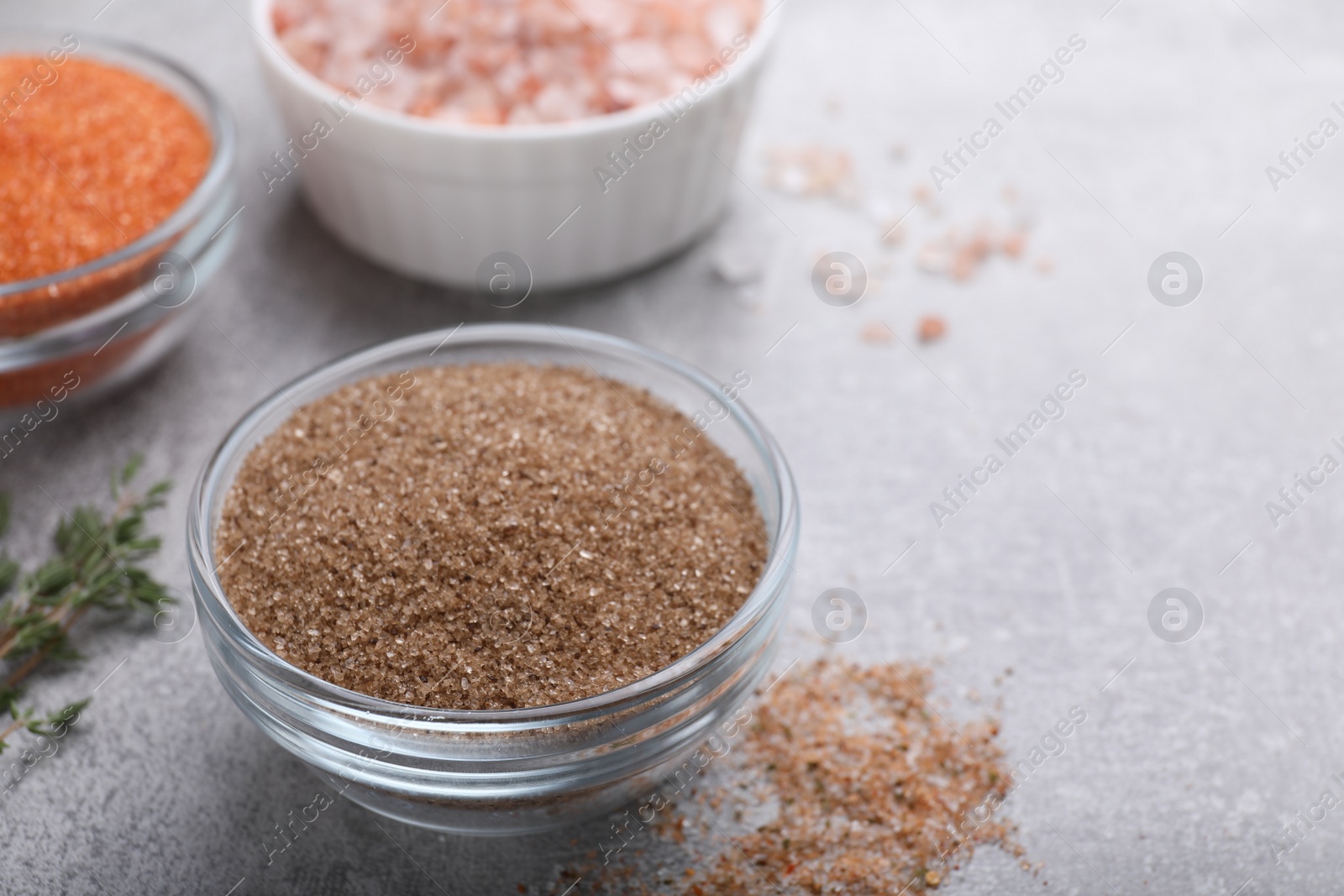 Photo of Different kinds of salt on grey table, space for text