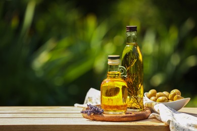 Photo of Different cooking oils and ingredients on wooden table against blurred green background, space for text
