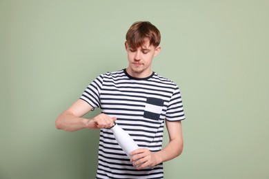 Man holding thermo bottle with drink on olive background
