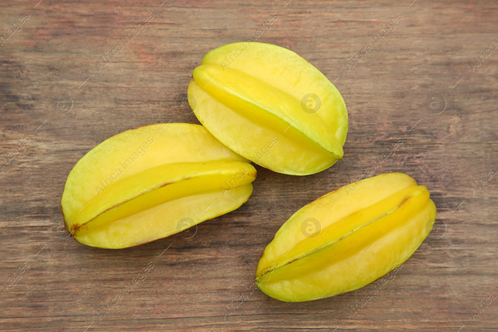 Photo of Delicious ripe carambolas on wooden table, flat lay