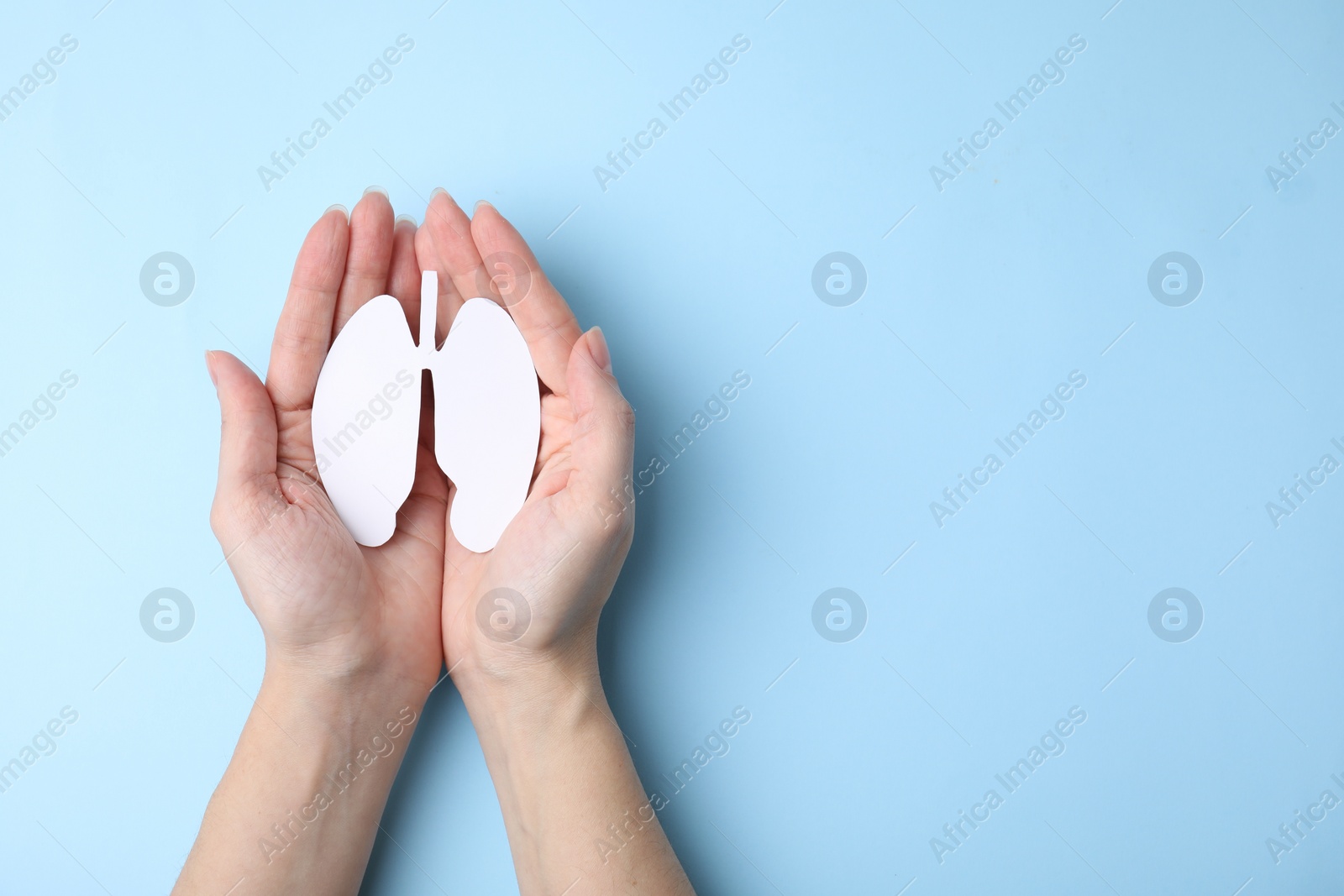 Photo of Quitting smoking concept. Woman holding paper lungs on light blue background, top view and space for text