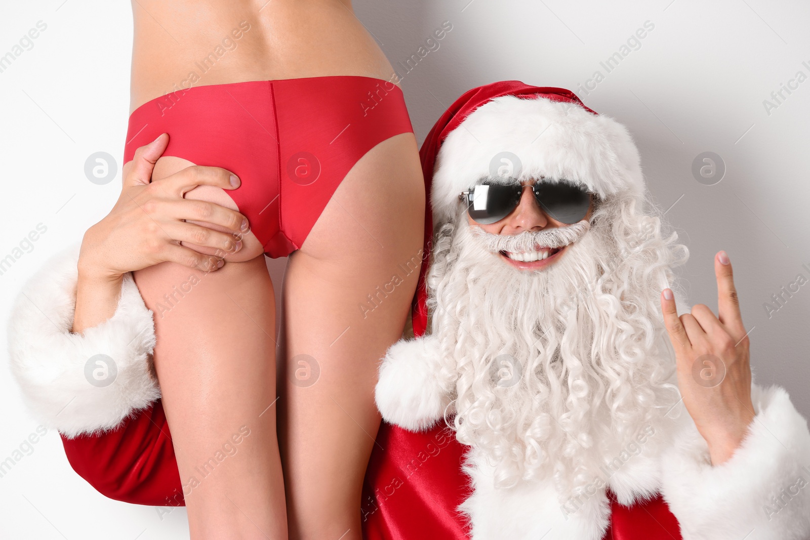 Photo of Young Santa Claus with sexy naked woman on white background