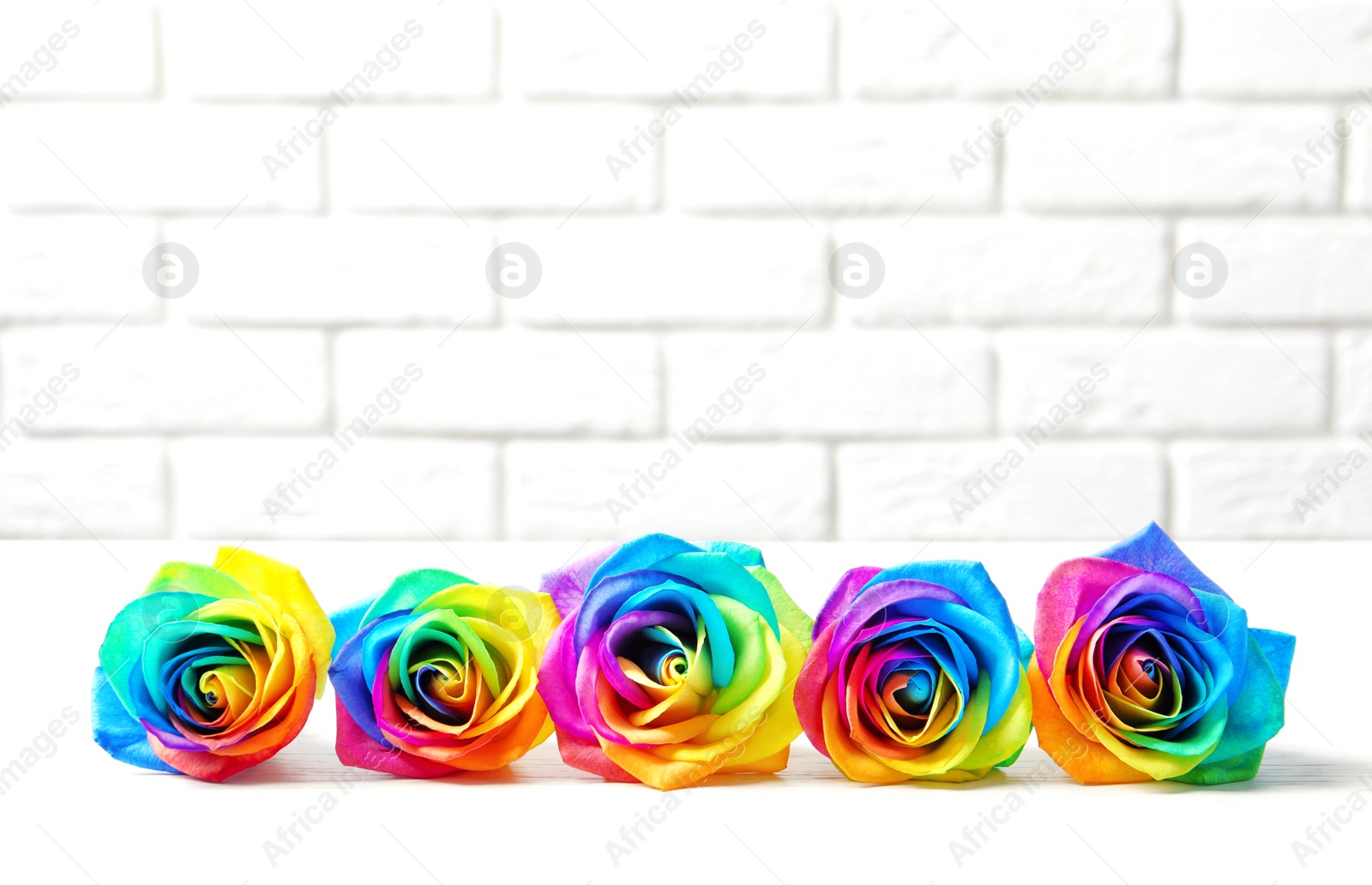 Photo of Amazing rainbow rose flowers on table