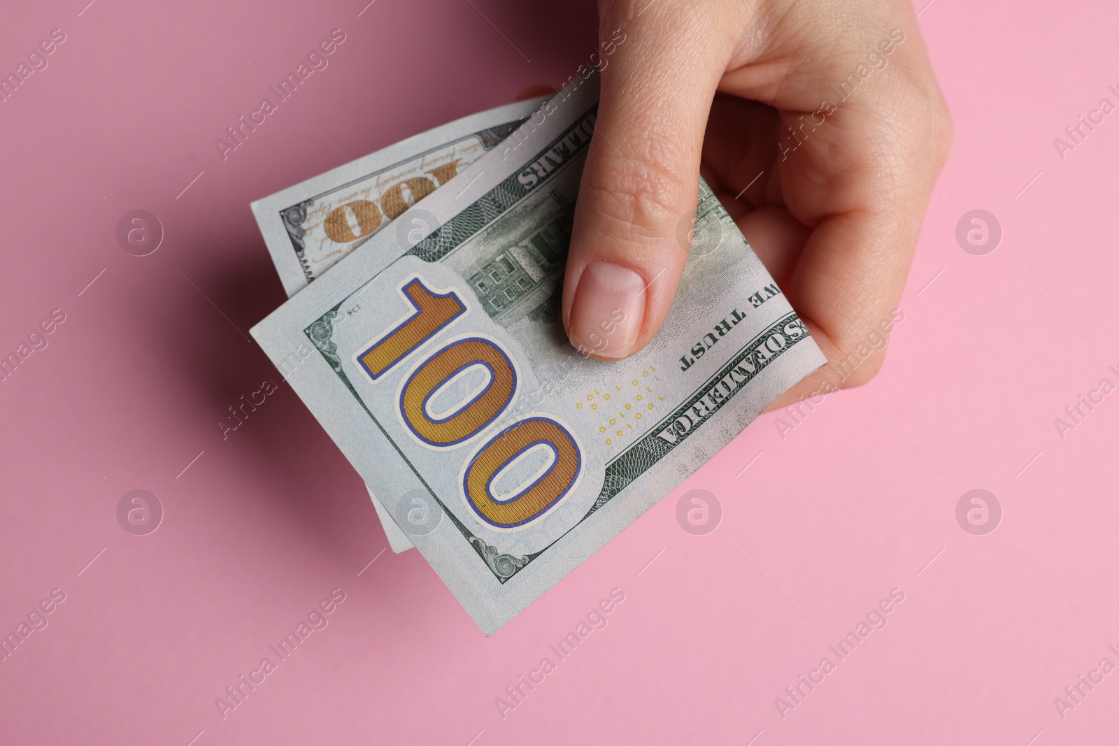 Photo of Money exchange. Woman holding dollar banknotes on pink background, top view