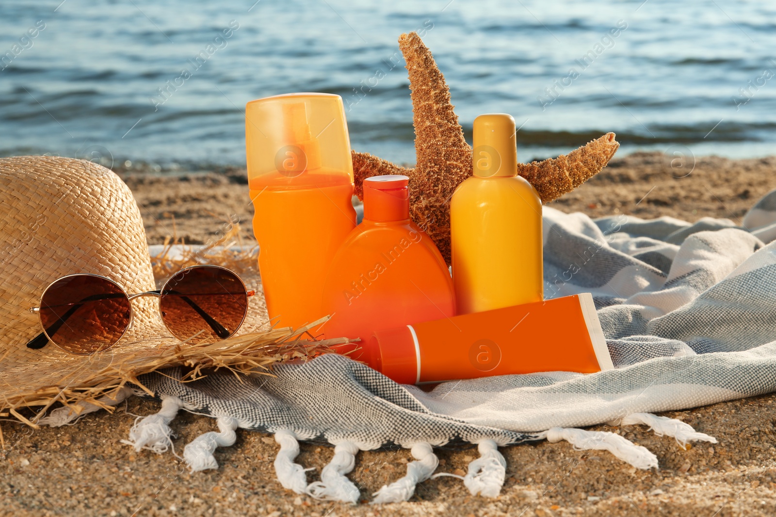 Photo of Sun protection products and beach accessories on blanket near sea