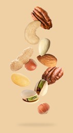 Many different nuts in air on beige background