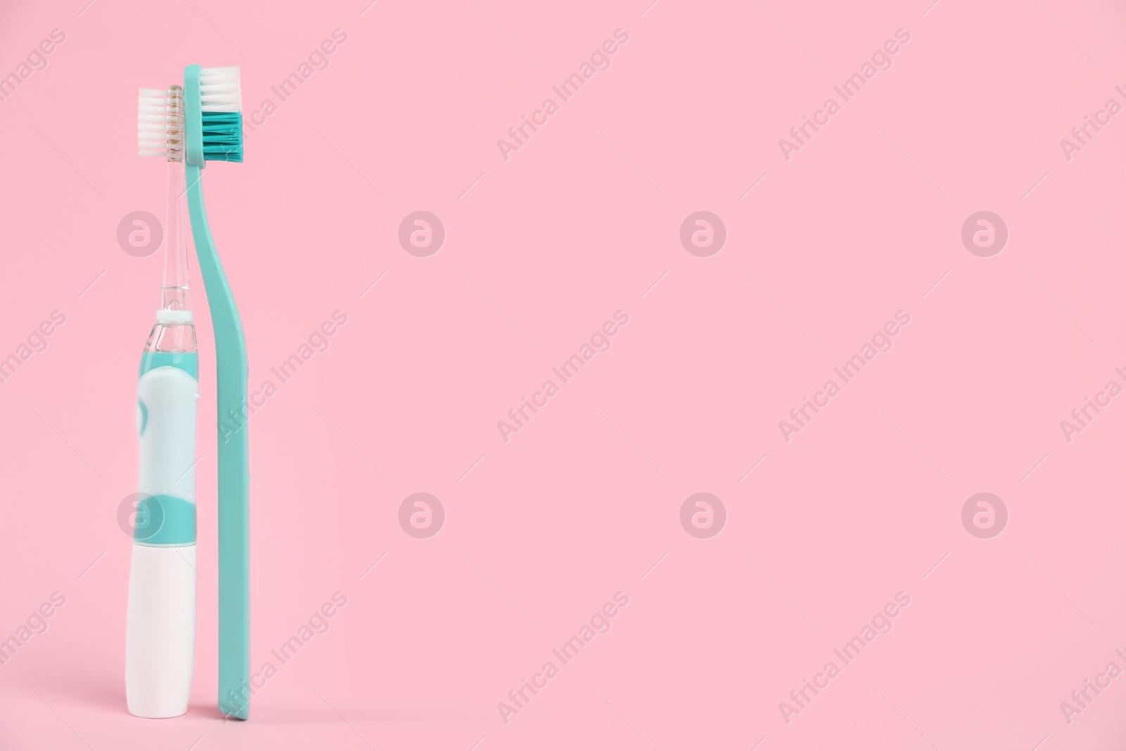 Photo of Electric and plastic toothbrushes on pink background, space for text