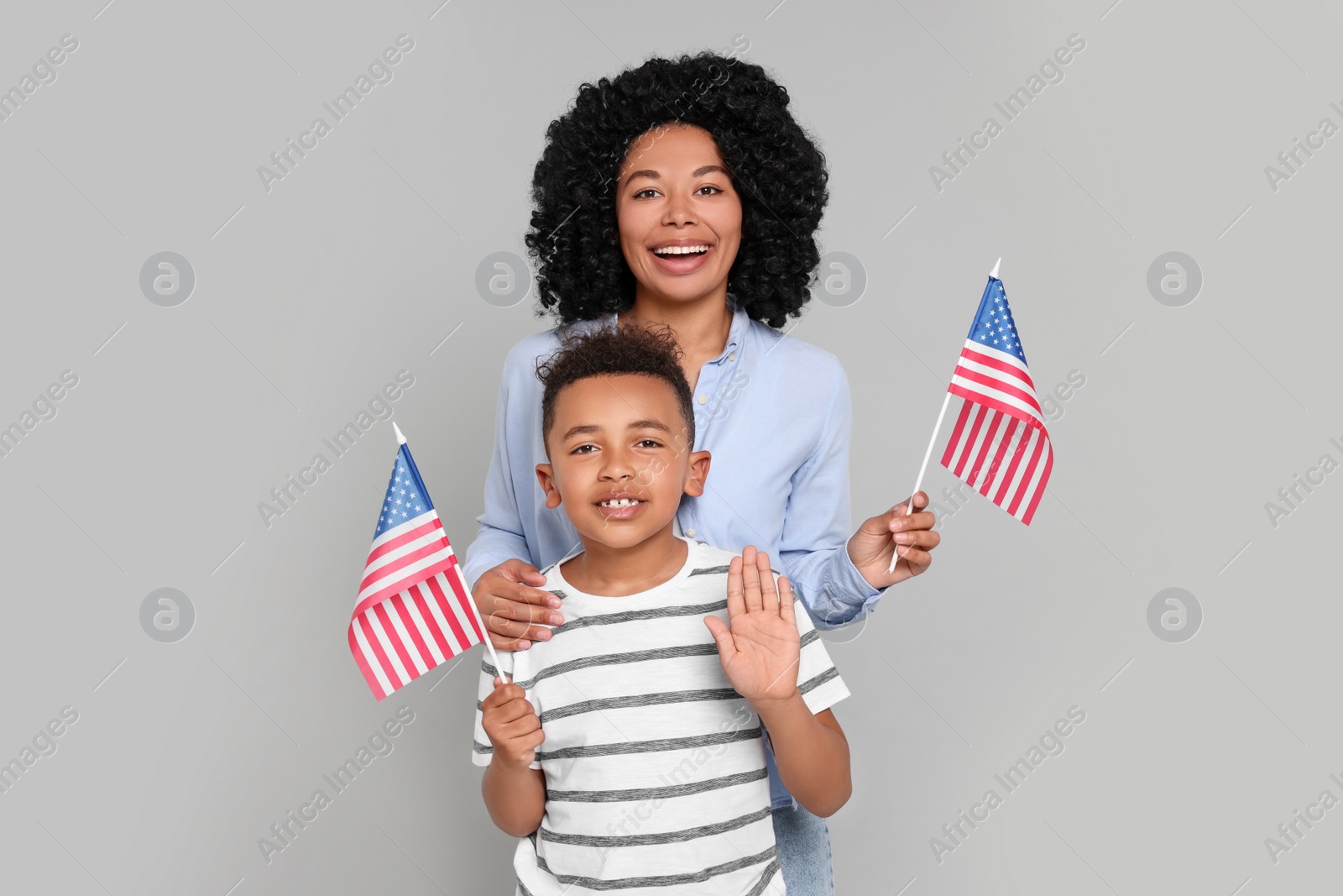 Photo of 4th of July - Independence Day of USA. Happy woman and her son with American flags on light grey background