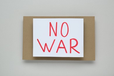 Photo of Paper card with phrase No War on light grey background, top view