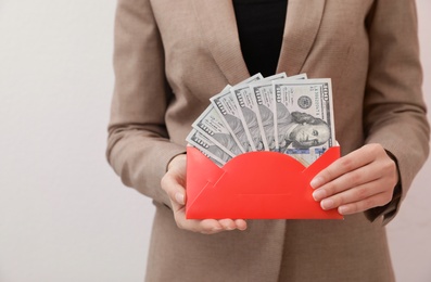 Photo of Woman holding envelope with dollar bills on white background, closeup