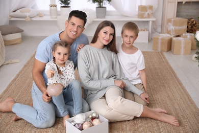 Photo of Happy family with box of Christmas ornaments at home