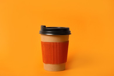 Takeaway paper coffee cup with cardboard sleeve on orange background