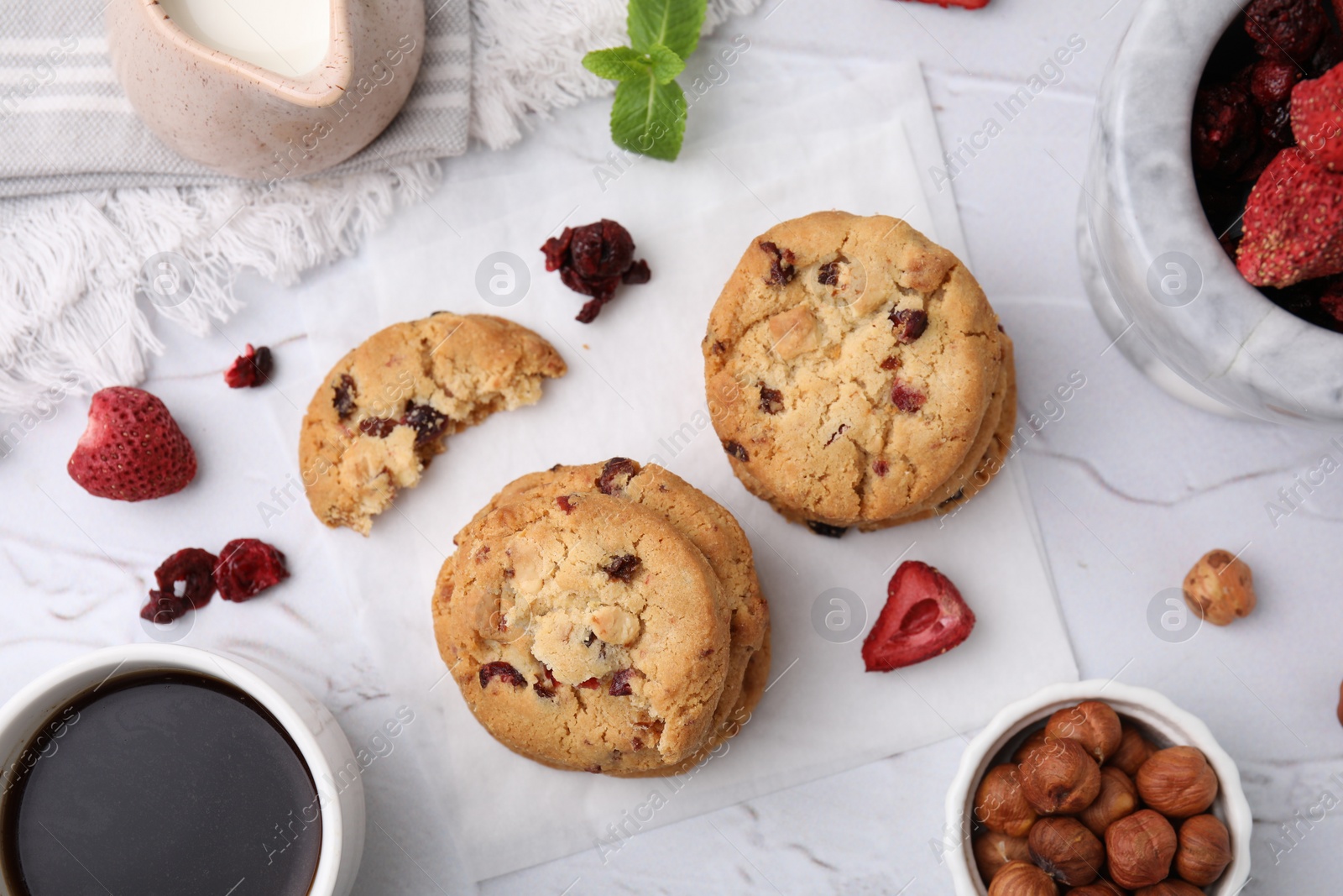 Cookies with freeze dried fruits, mint, milk, coffee and nuts on white textured table, flat lay Photo of Cookies with freeze dried fruits, mint, milk, coffee and nuts on white textured table, flat lay
