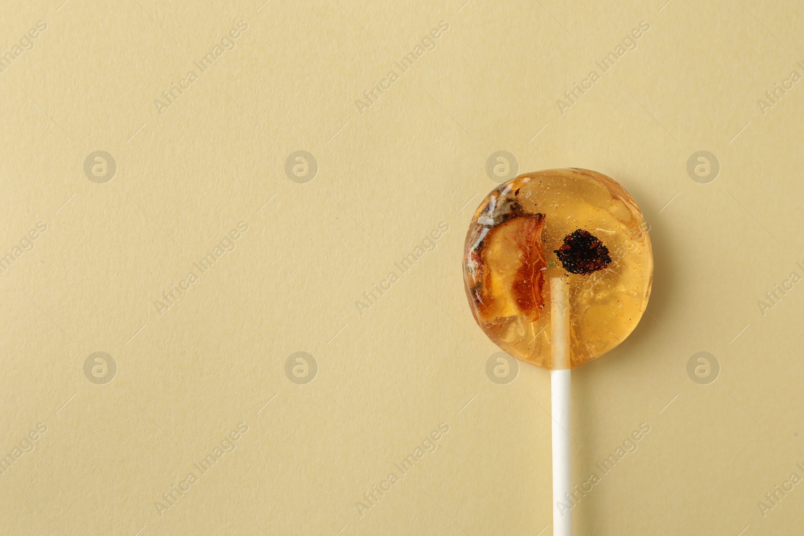 Photo of Sweet colorful lollipop with berries on beige background, top view. Space for text