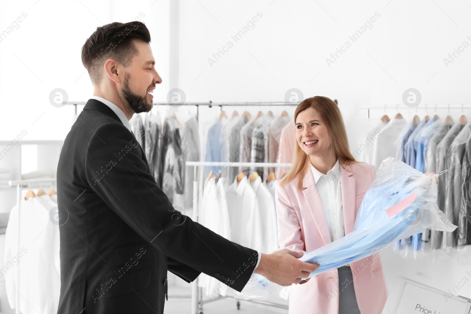 Photo of Dry-cleaner's worker giving shirt to businessman