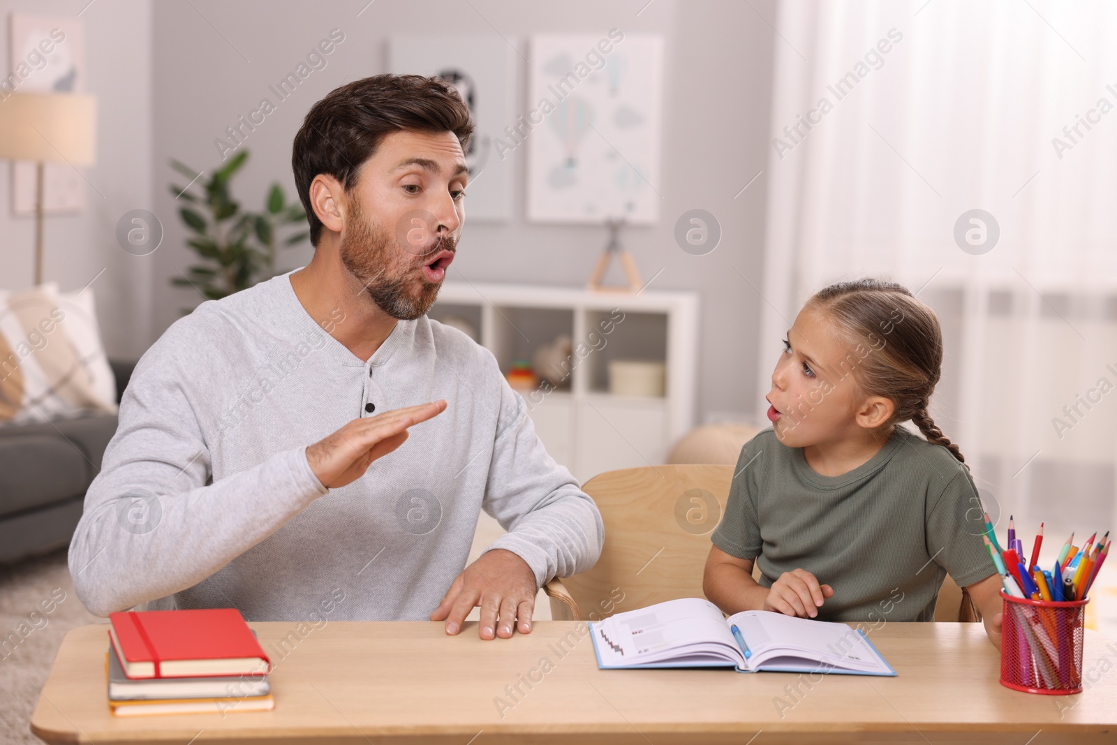 Photo of Dyslexia problem. Father working with daughter at table in room