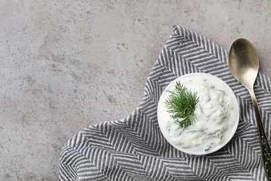 Photo of Cucumber sauce, spoon and space for text on grey background, flat lay. Traditional Tzatziki