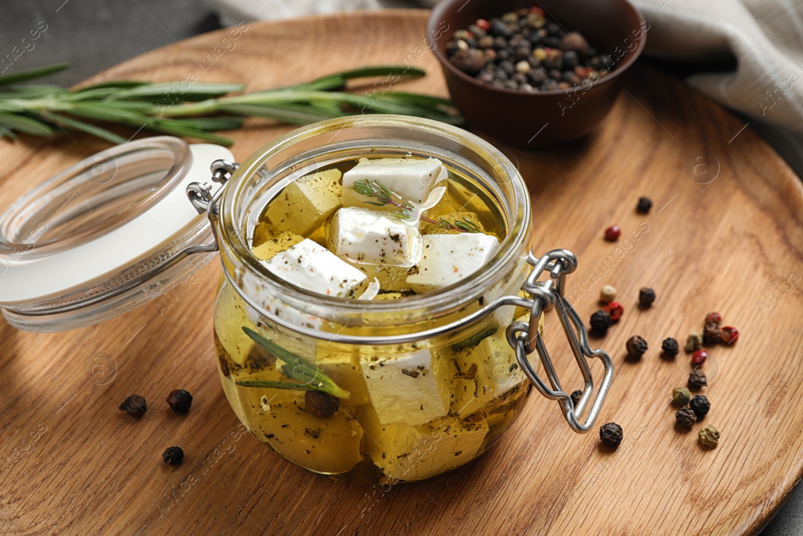 Photo of Jar with feta cheese marinated in oil on table. Pickled food