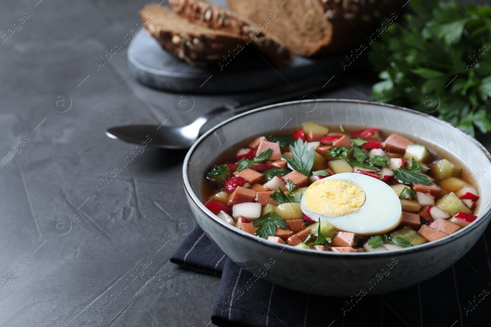 Photo of Delicious cold okroshka with kvass served on grey table. Traditional Russian summer soup