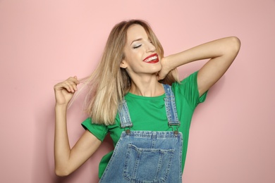 Beautiful young woman with healthy long blonde hair on color background