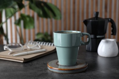 Photo of Mug of hot drink with stylish cup coaster on grey table