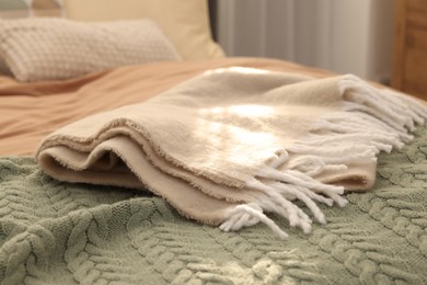 Photo of Soft blankets on bed indoors, closeup. Home textile