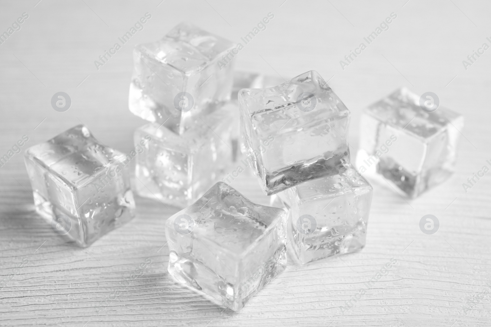 Photo of Ice cubes with water drops on white wooden table, closeup