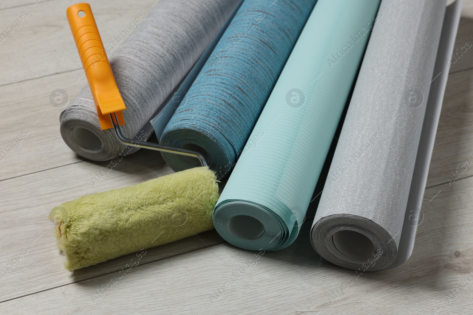 Photo of Different wallpaper rolls and roller on floor