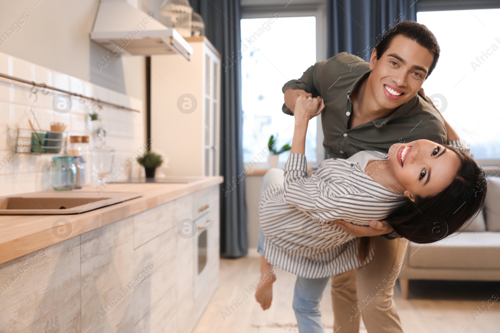 Photo of Lovely young interracial couple dancing at home. Space for text