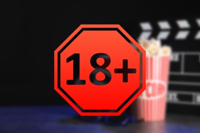 Age limit sign 18+ years and blurred view of clapperboard with popcorn