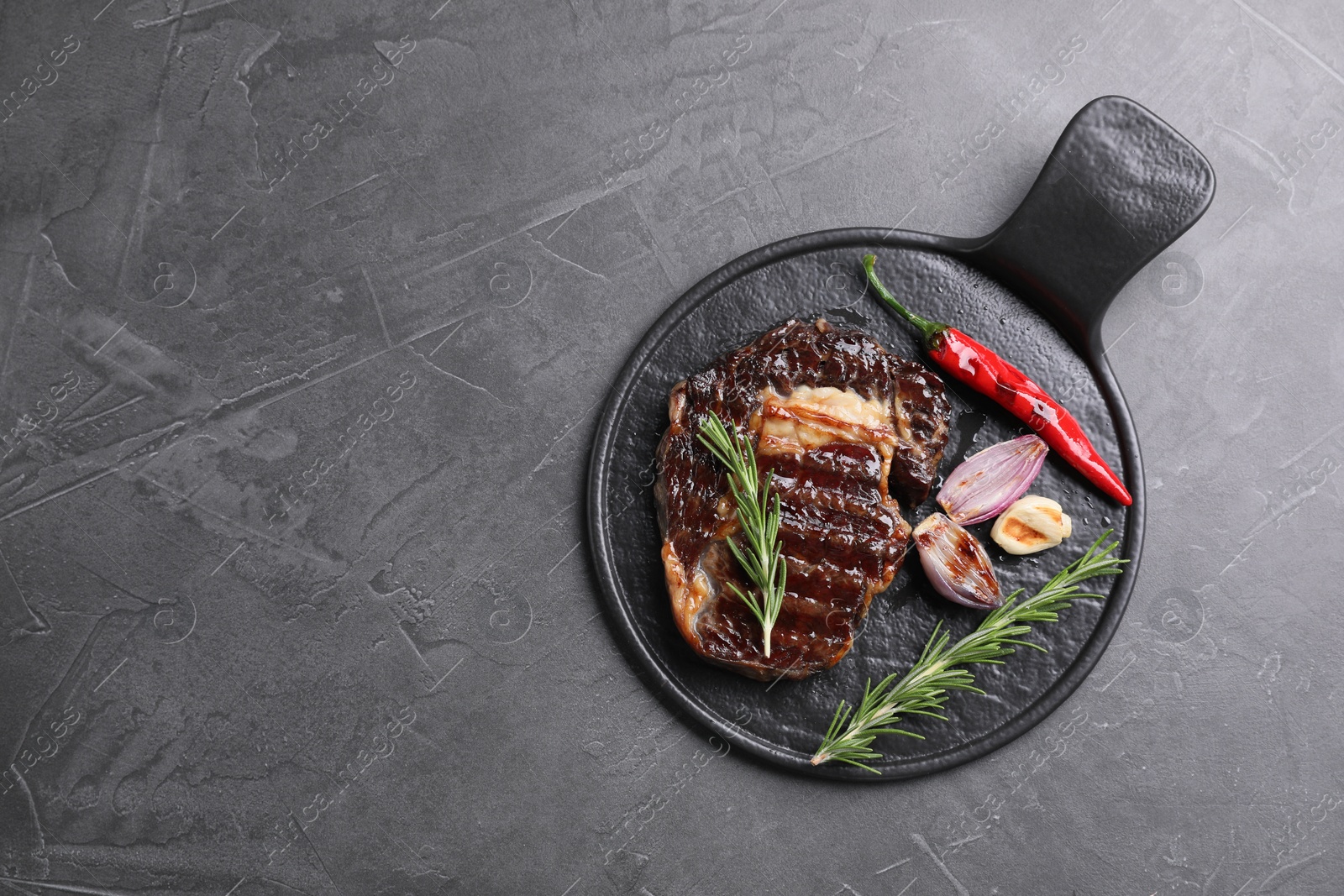 Photo of Delicious grilled beef meat, rosemary and spices on gray textured table, top view. Space for text