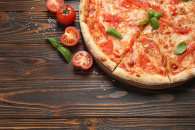 Photo of Delicious pizza Margherita and ingredients on wooden table, flat lay. Space for text